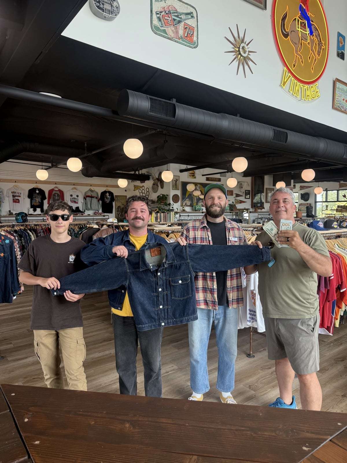 The team at Old 44 Vintage holding up a vintage denim jacket while cash changes hands