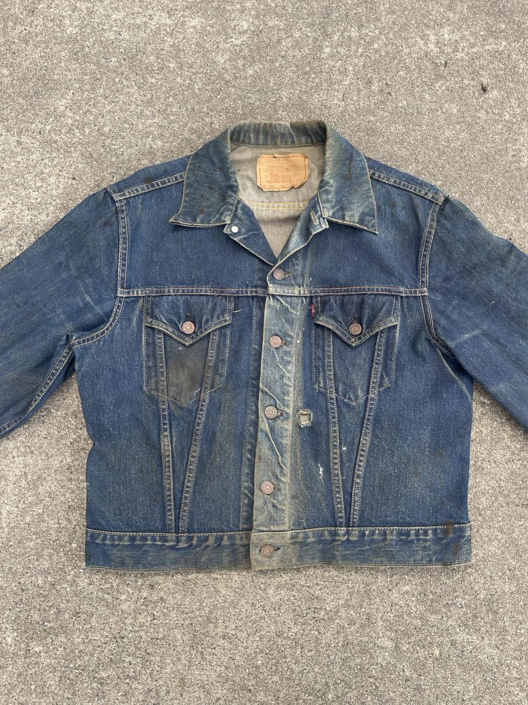 Well worn 1960s Levi's 557XX Type 3 trucker jacket laid flat on concrete