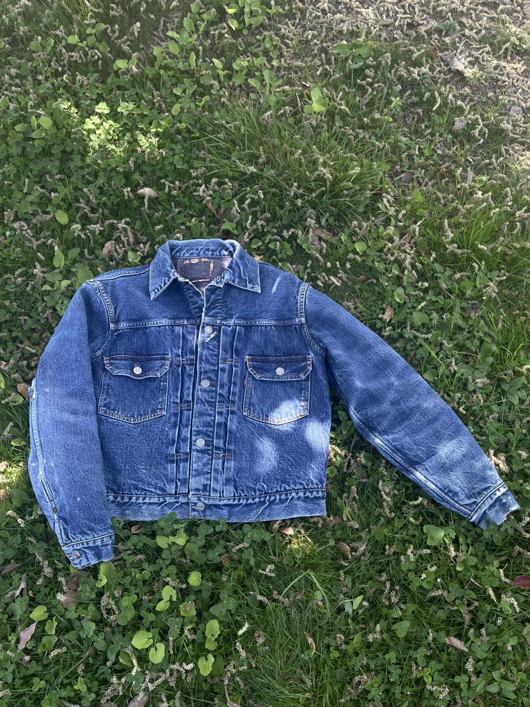 Faded vintage Levi's trucker jacket with red tab, laid flat outdoors
