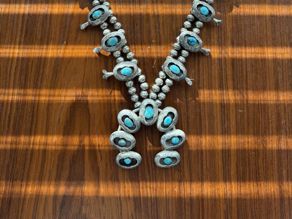 Shadowbox squash blossom necklace with turquoise stones and naja, laid flat on a wood table for identification