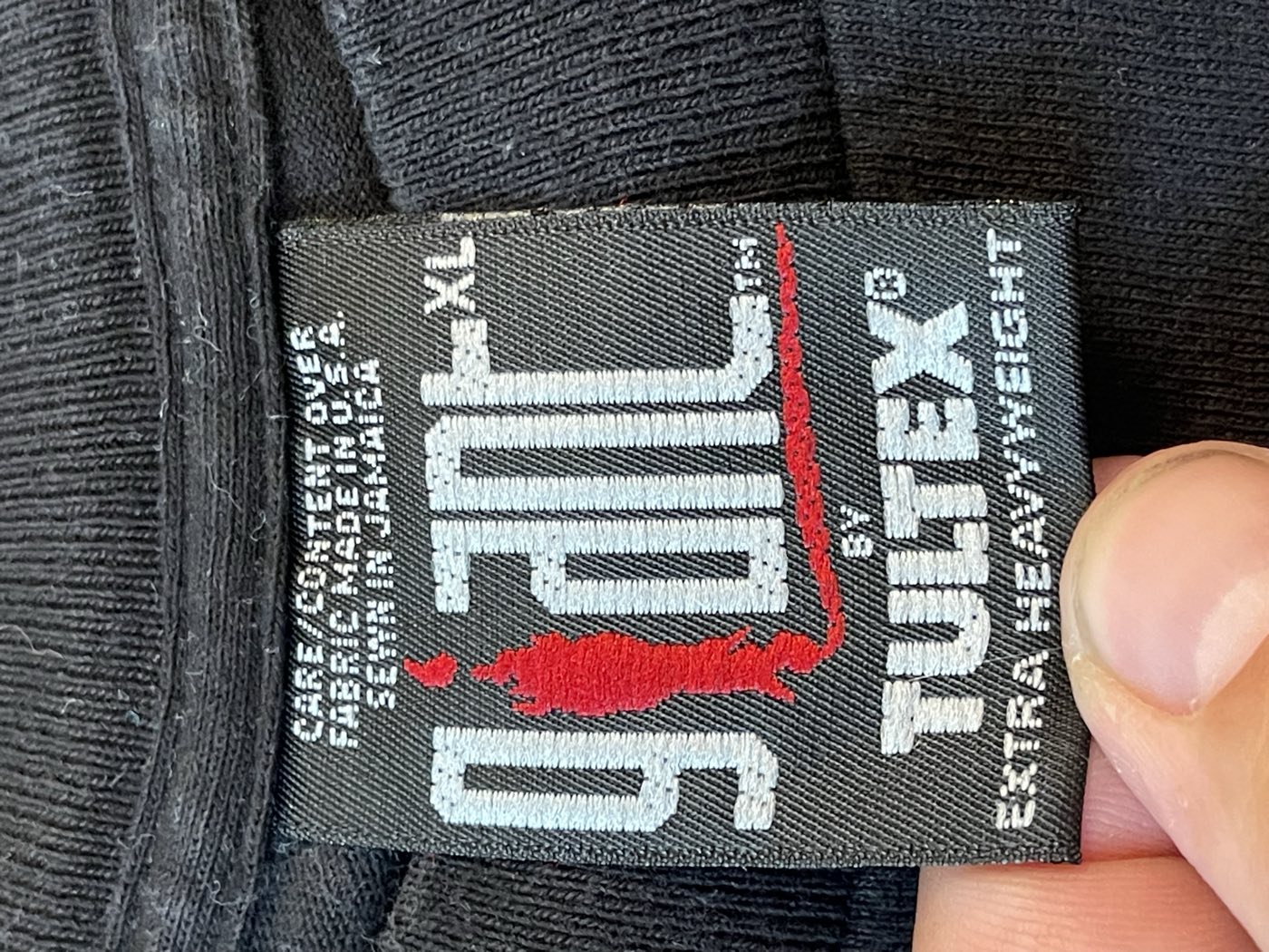Black woven Giant by Tultex extra heavyweight tag, size XL, reading care and content over, fabric made in U.S.A., sewn in Jamaica, inside a Flaming Lips t-shirt