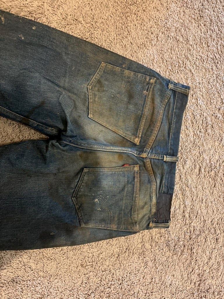 Back view of the same vintage Levi's jeans showing back pockets, red tab, and a darkened leather patch remnant at the waistband