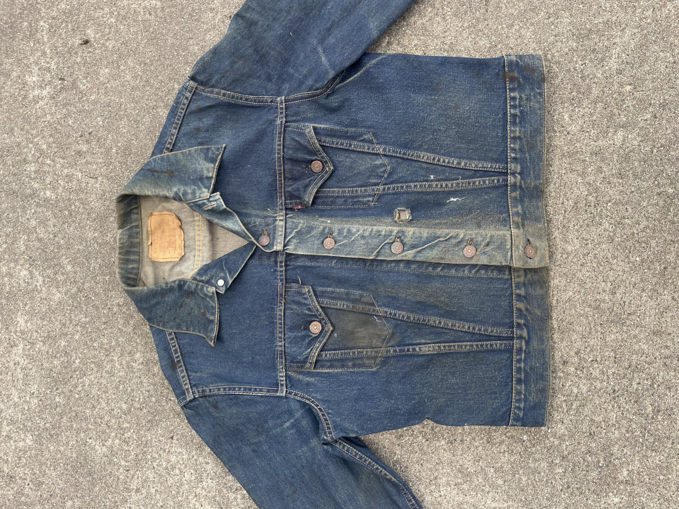 Well worn 1960s Levi's 557XX Type 3 trucker jacket laid flat, paper patch at the collar and red tab on the chest pocket