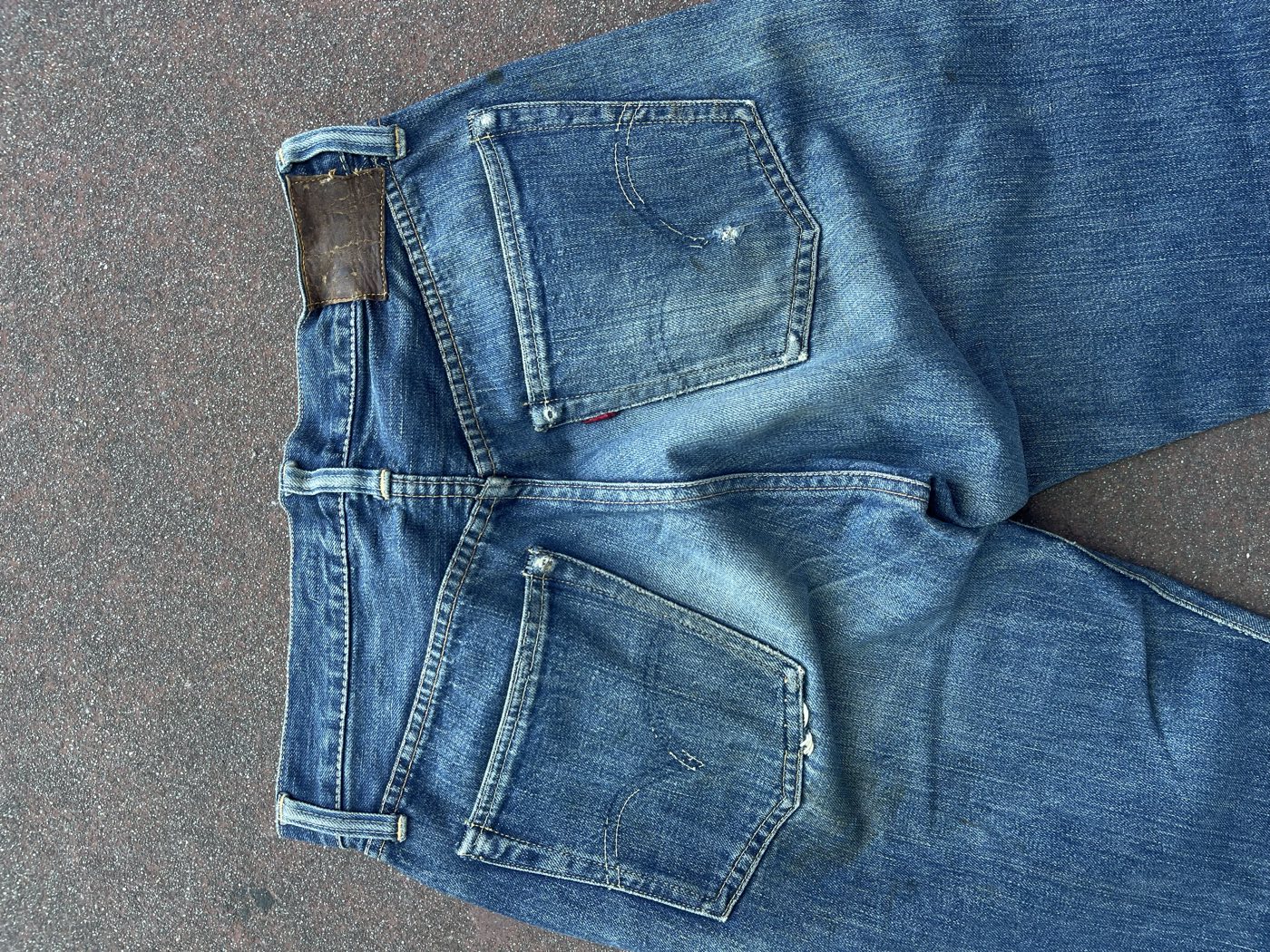 Back waistband of vintage Levi's jeans showing a dried leather two-horse patch beside the red tab