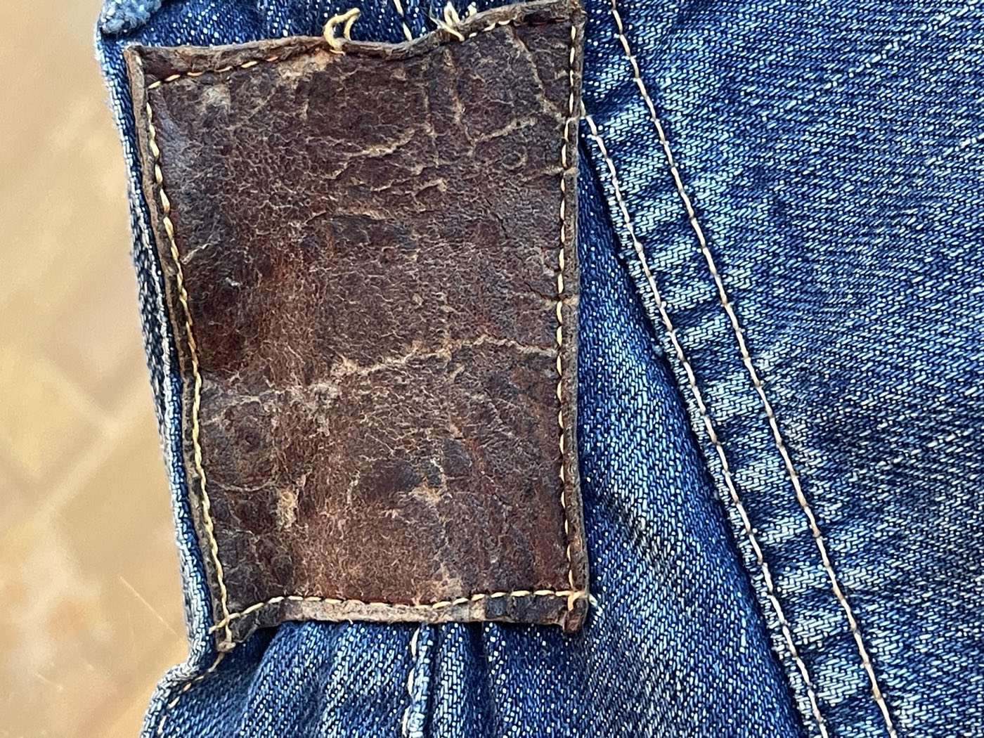 Dark brown leather Levi's patch, cracked and worn illegible, on a pair of vintage jeans