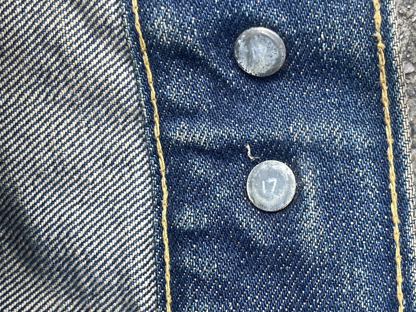 Two silver Levi's back buttons stamped with the number 17 on the inside placket of a vintage trucker jacket