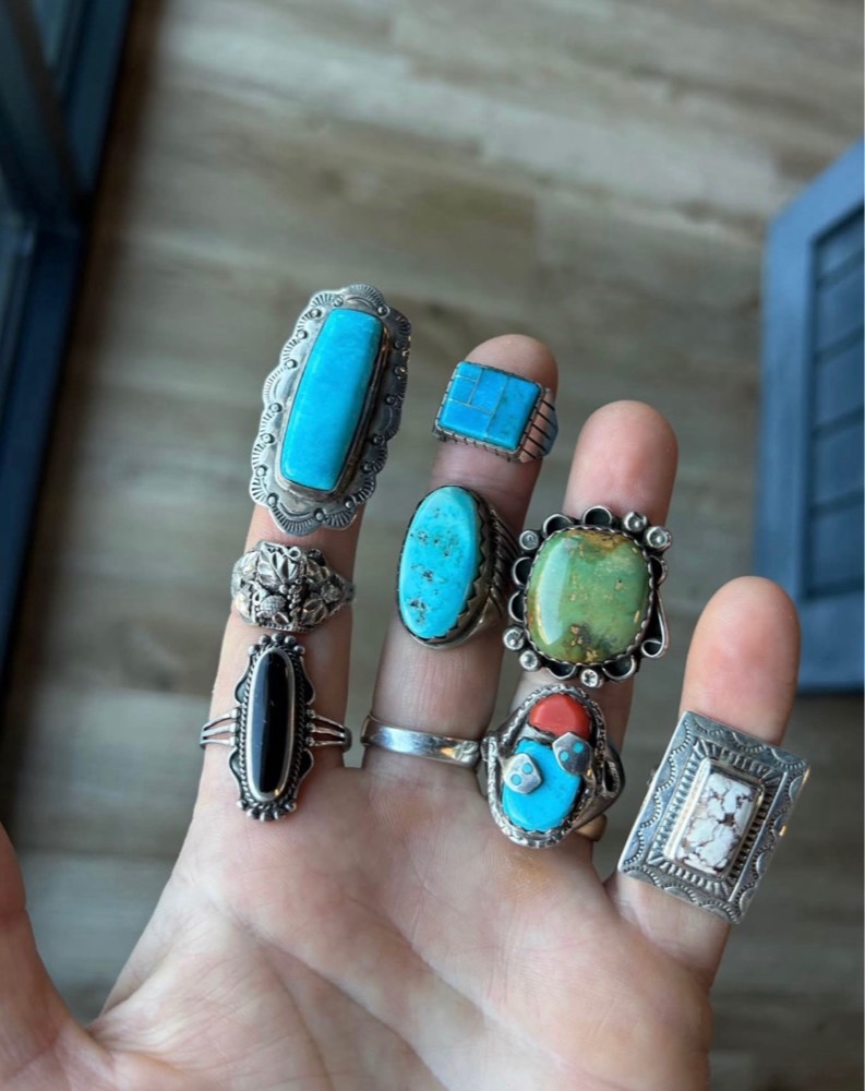 Eight vintage turquoise and silver rings shown across a hand